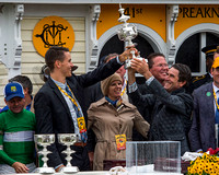 Assistant Trainer Julie Clark (center) smiles as Preakness winning trainer Keith Desormeaux (right) hoists the trophy with one of the owners at Pimlico Race Course in Baltimore, Maryland.
